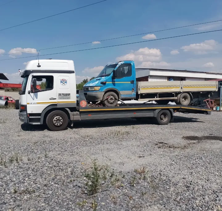 Plavo lako teretno vozilo na platformi kamiona.